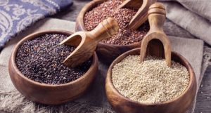 دانه‌های کینوا در کاسه سفید روی پس‌زمینه چوبی